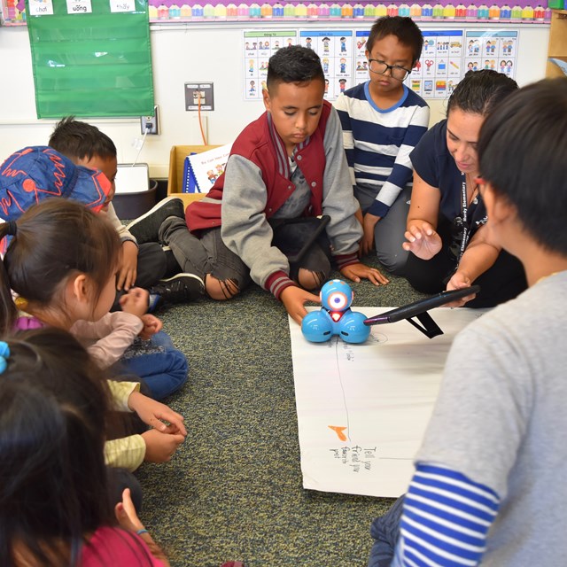 4th grade students help teach TK students to code robots. 