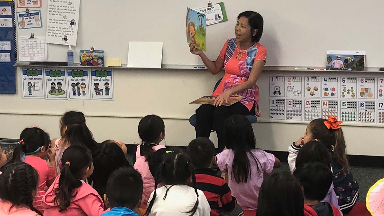teacher reading a book to students